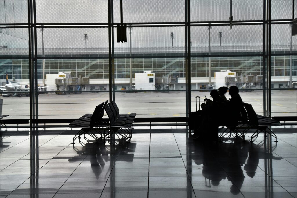 Traveler waiting at an airport gate with luggage and documents.