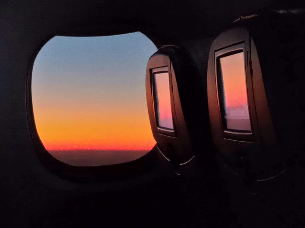 Airplane window sunrise for long flight health hacks and jet lag planning